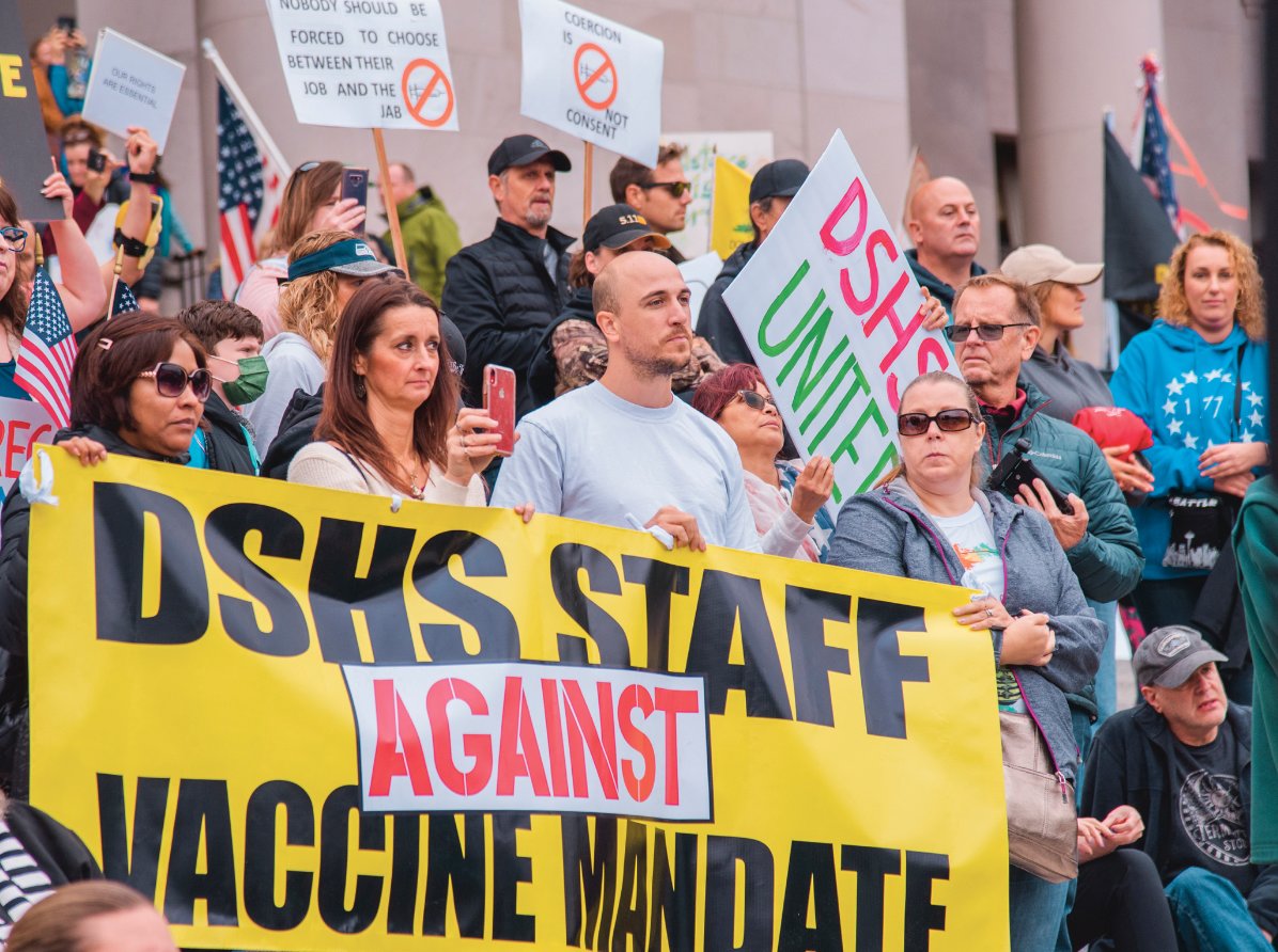 Washington Department of Social and Health Services employees against the vaccine mandate stand and hold signs alongside other rally goers on the steps of the Washington State Capitol Building in Olympia on Sunday.
